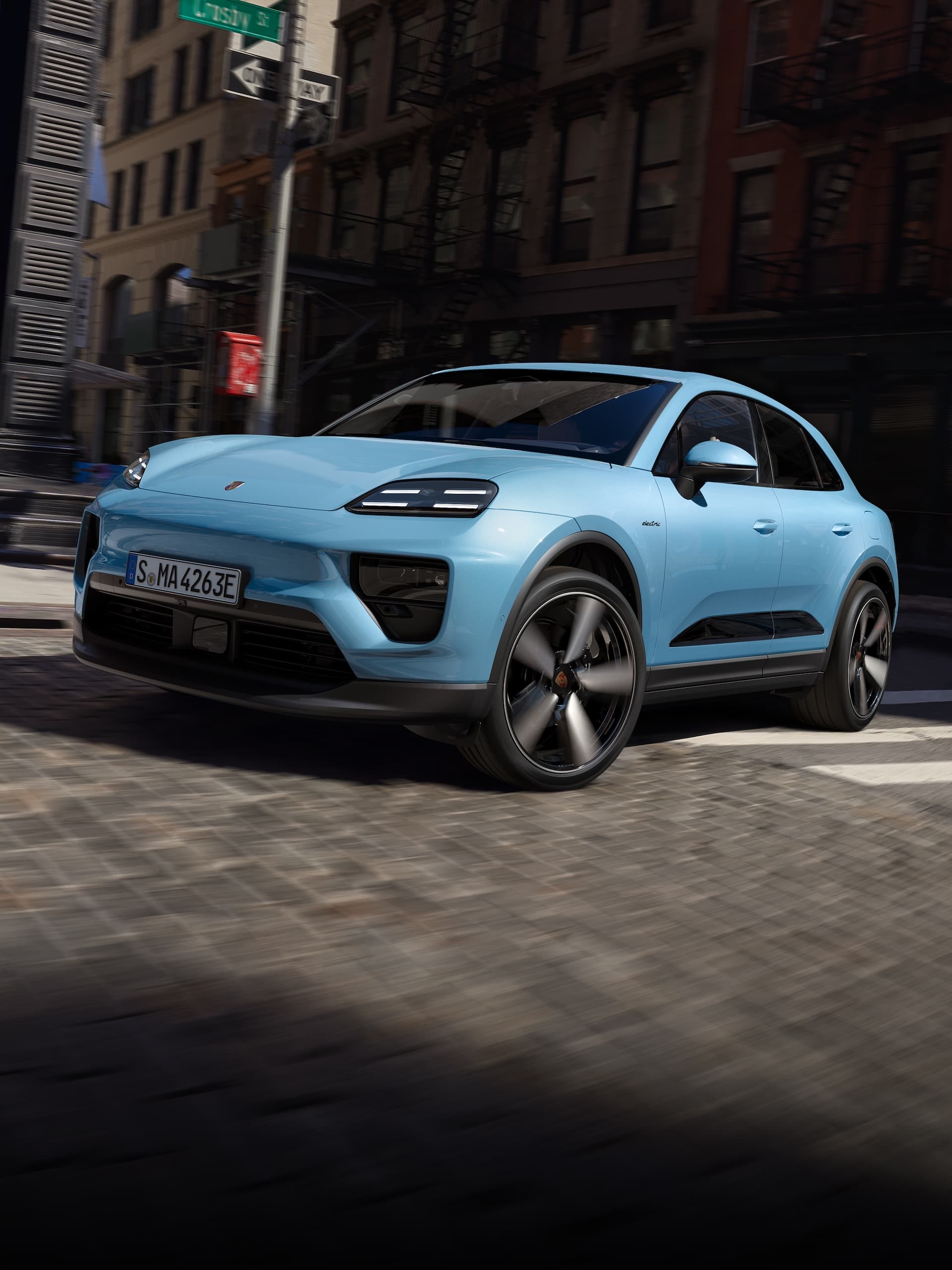 A Porsche all-electric Macan driving down a road in an urban scenario.